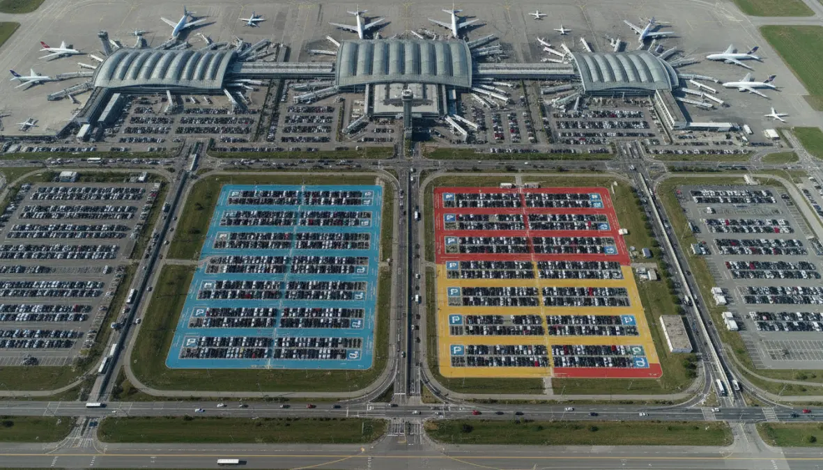 Aerial view of European airport showing on-site and off-site parking facilities with different pricing zones