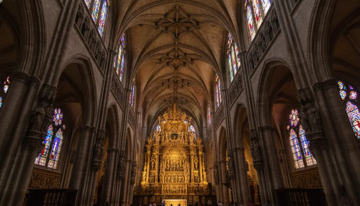 Gothic interior of Seville Cathedral showing ornate golden altarpiece and soaring vaulted ceilings